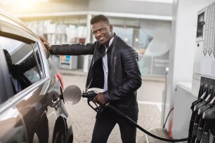 A young man fills his car with gas.