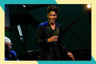 Jon Batiste smiles onstage with a microphone in hand.