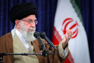 Ali Khamenei with flag of Iran behind him