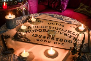Spiritism table with a Ouija board and many lighted candles. Esoteric seance on Halloween