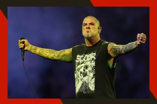 Pantera frontman Phil Anselmo embraces the crowd from the stage with a microphone in hand.